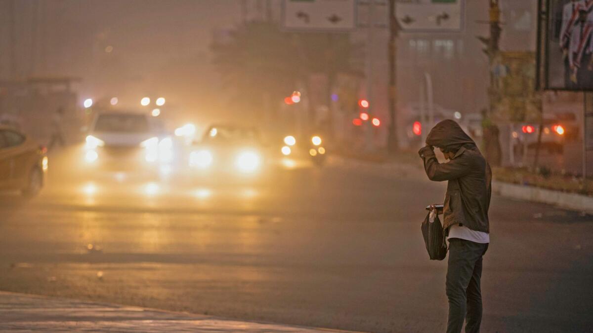 A man stands on the roadside in Baghdad as thick dust blankets the city, on Friday. — AFP