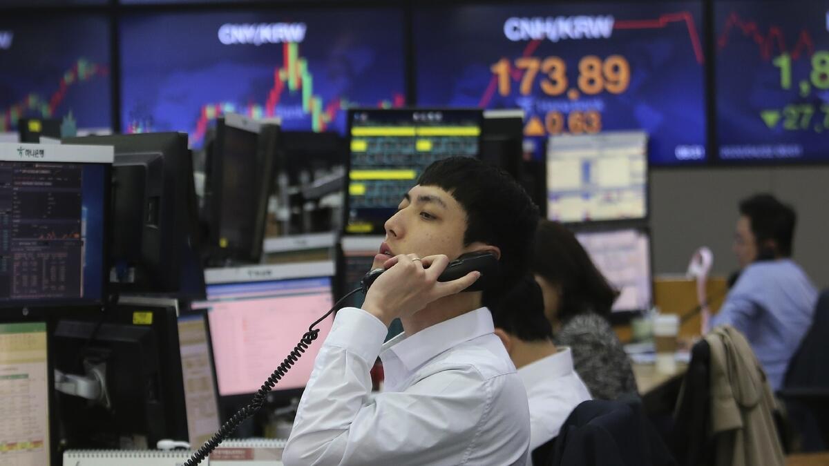 A currency trader talks on the phone at the foreign exchange dealing room of the KEB Hana Bank headquarters in Seoul, South Korea, on Wednesday. Asian stock markets fell further as oil prices recovered some of their record-setting losses amid anxiety about the coronavirus pandemic's mounting economic damage. - AP