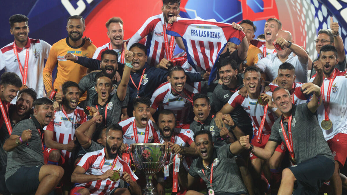 ATK players pose with the trophy after defeating Chennaiyin in the final on Saturday. - AFP