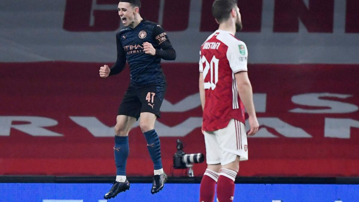 Manchester City's Phil Foden celebrates scoring their third goal as Arsenal's Shkodran Mustafi looks dejected.