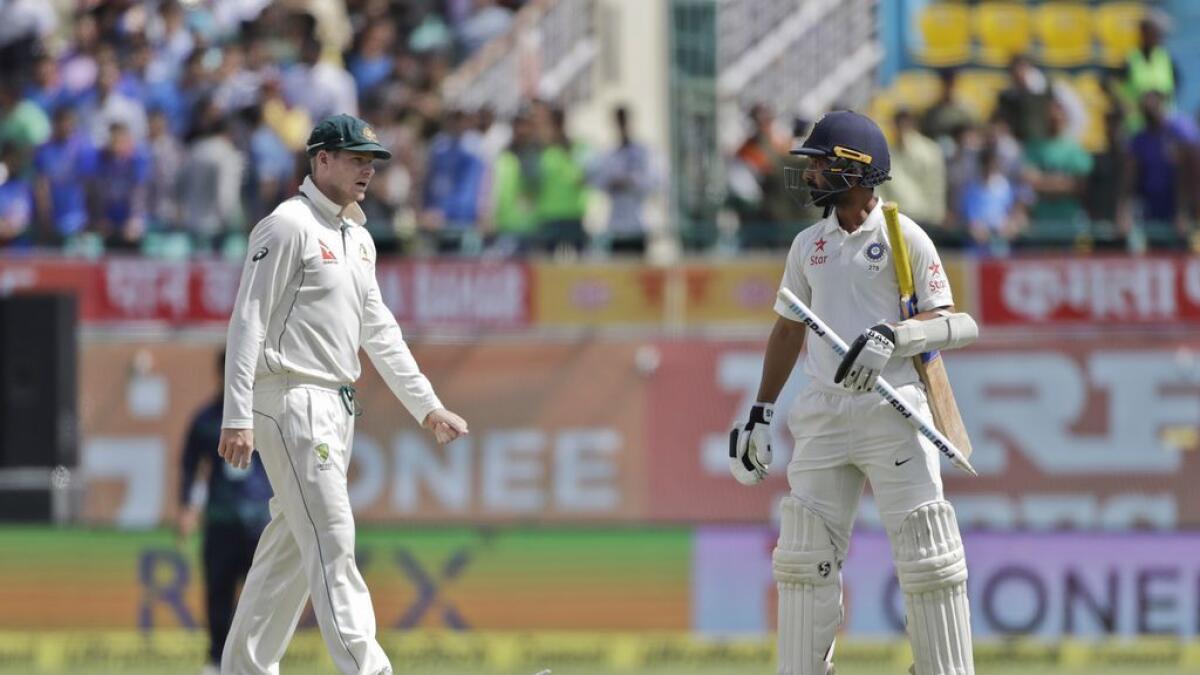 Australia's captain Steven Smith, left, walks towards India's Ajinkya Rahane, carrying a stump after India won their fourth test cricket match against Australia in Dharmsala  on Tuesday