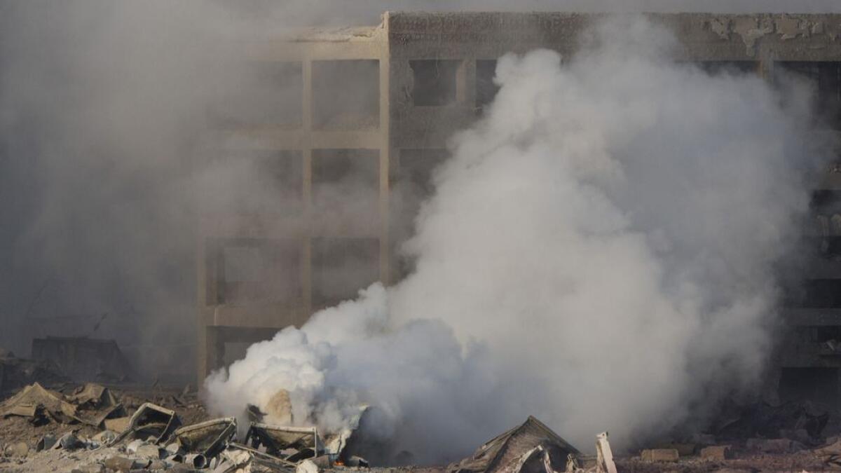 A firefighter in protective overalls walks past smoke rising from the site of an explosion that destroyed large swathes of at a port warehouse in northeastern Chinas Tianjin municipality.