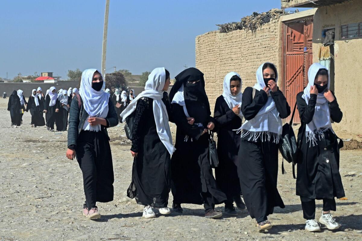 Afghan school girls walk along a path as they return from school in Mazar-i-Sharif on October 30, 2021.   — AFP