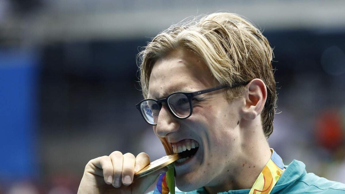 Mack Horton bites his medal on the podium. — AFP