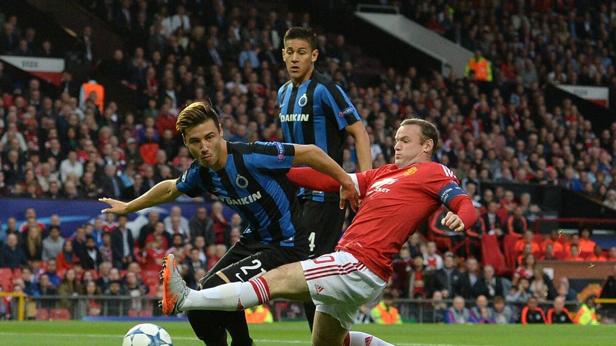 United’s Wayne Rooney is challenged by Brugge’s Dion Cools (left) during their Uefa Champions League playoff match. 