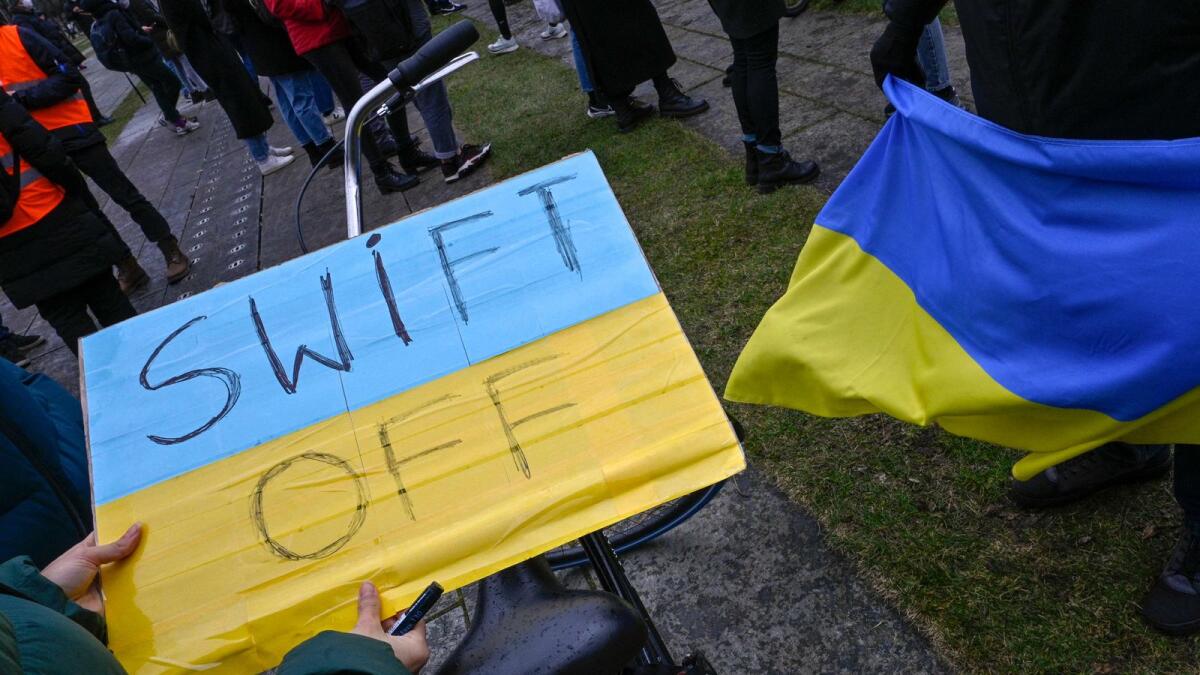A demonstrator holds a placard reading 'SWIFT OFF', refering to the international SWIFT financial transfer networkduring a protest against Russia's invasion of the Ukraine. — AFP