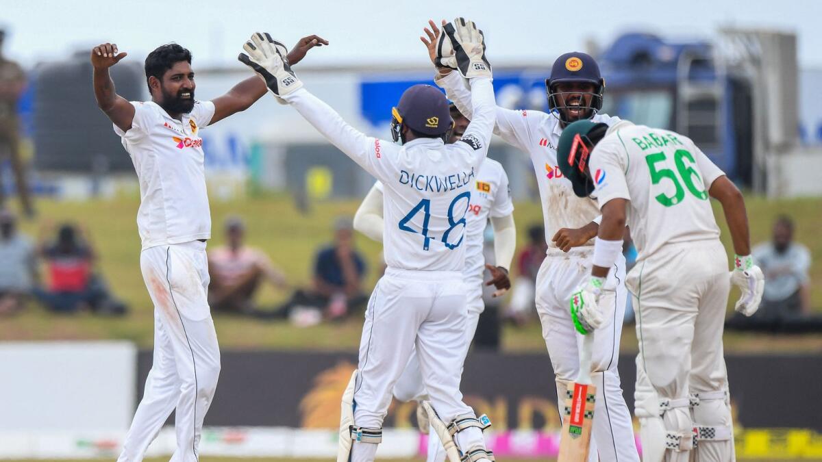 Sri Lanka's Prabath Jayasuriya (left) celebrates with teammates after taking the wicket of Pakistan's Babar Azam (right) during the final day of the second Test in Galle on Thursday. — AFP