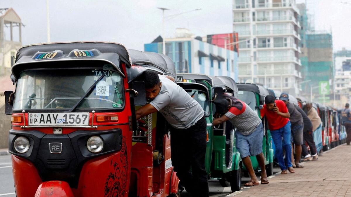 Drivers push auto rickshaws in a line to buy petrol from a fuel station amid Sri Lanka's economic crisis, in Colombo, Sri Lanka, July 29, 2022. — Reuters