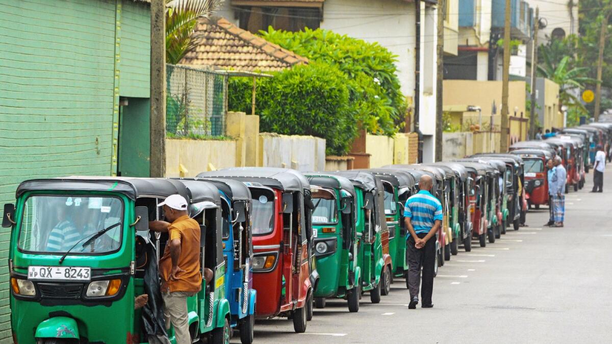 Auto rickshaw drivers queue along a street to buy fuel at a fuel station in Colombo on July 3, 2022. Photo: AFP