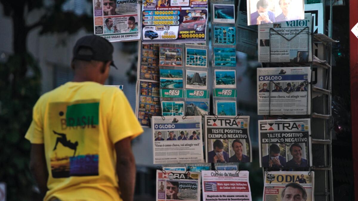 A man looks at the front pages of newspapers with the news of Brazilian President Jair Bolsonaro being a confirmed case of the new coronavirus, at a newsstand in Rio de Janeiro, Brazil. Photo: AFP