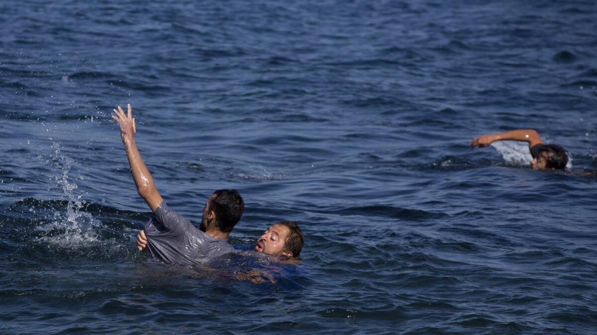 Local resident Dimitris Karapanagiotis, centre,  rescues an Afghan migrant whose boat stalled at sea while crossing with others from Turkey to the island of Lesbos, Greece, on Sept. 19, 2015. 