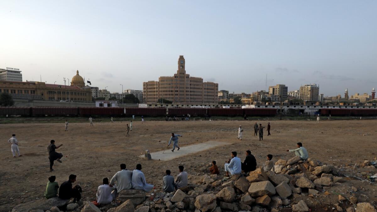 A man makes a run as he along with others plays cricket while people watching in an open space with the financial district's buildings in the background, as the outbreak of the coronavirus disease (Covid-19) continues, in Karachi, Pakistan. Photo: Reuters