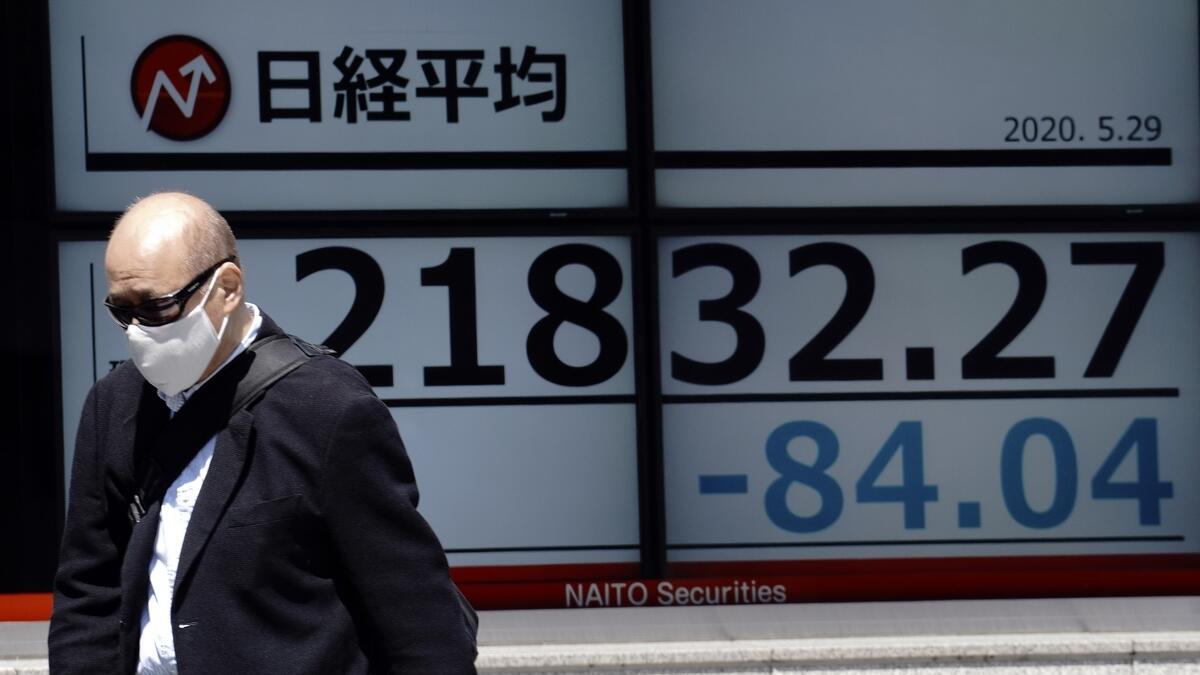 A man walks past an electronic stock board showing Japan's Nikkei 225 index at a securities firm in Tokyo on Friday. - AP