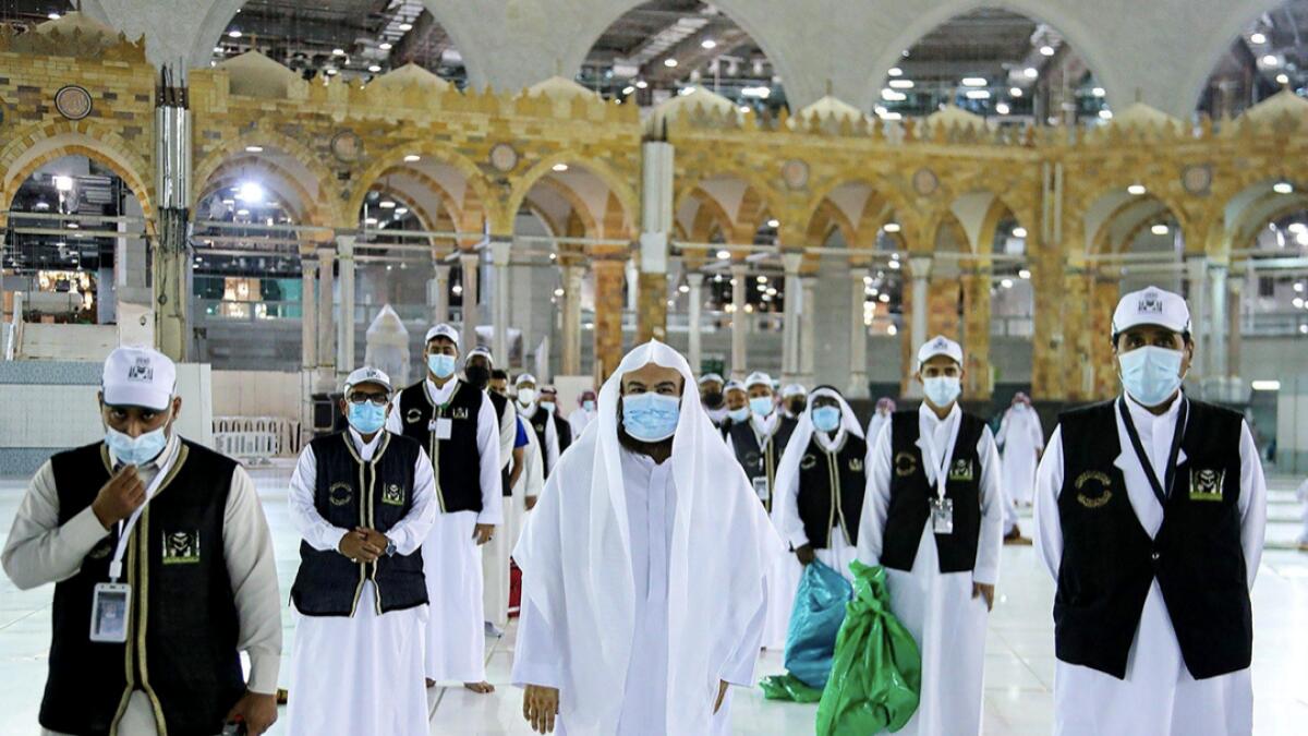 Men wearing protective face masks stand as they work on raising the Kiswa, a silk cloth covering the Holy Kaaba, before the annual pilgrimage season, at the Grand Mosque in Makkah, Saudi Arabia. Photo: Reuters