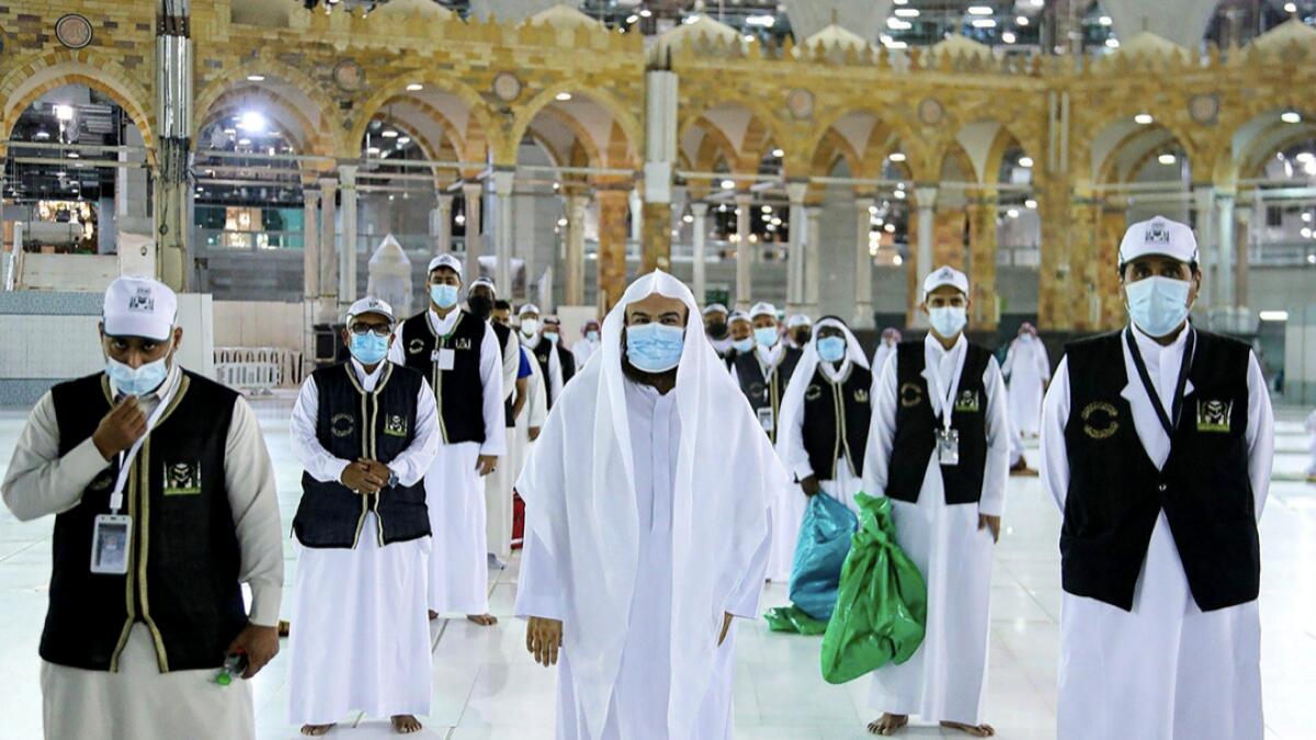 Men wearing protective face masks stand as they work on raising the Kiswa, a silk cloth covering the Holy Kaaba, before the annual pilgrimage season, at the Grand Mosque in Makkah, Saudi Arabia. Photo: Reuters