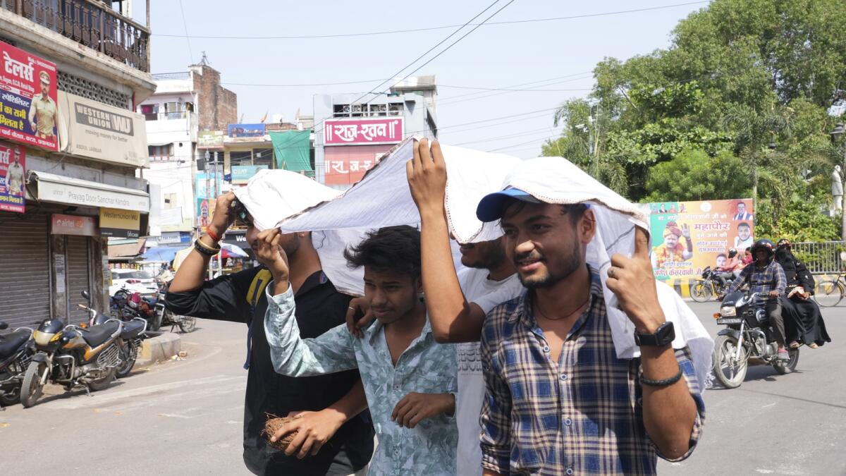 Youth share a piece of cloth to protect themselves from the sun on a hot summer day in Prayagraj, northern Uttar Pradesh. — AP