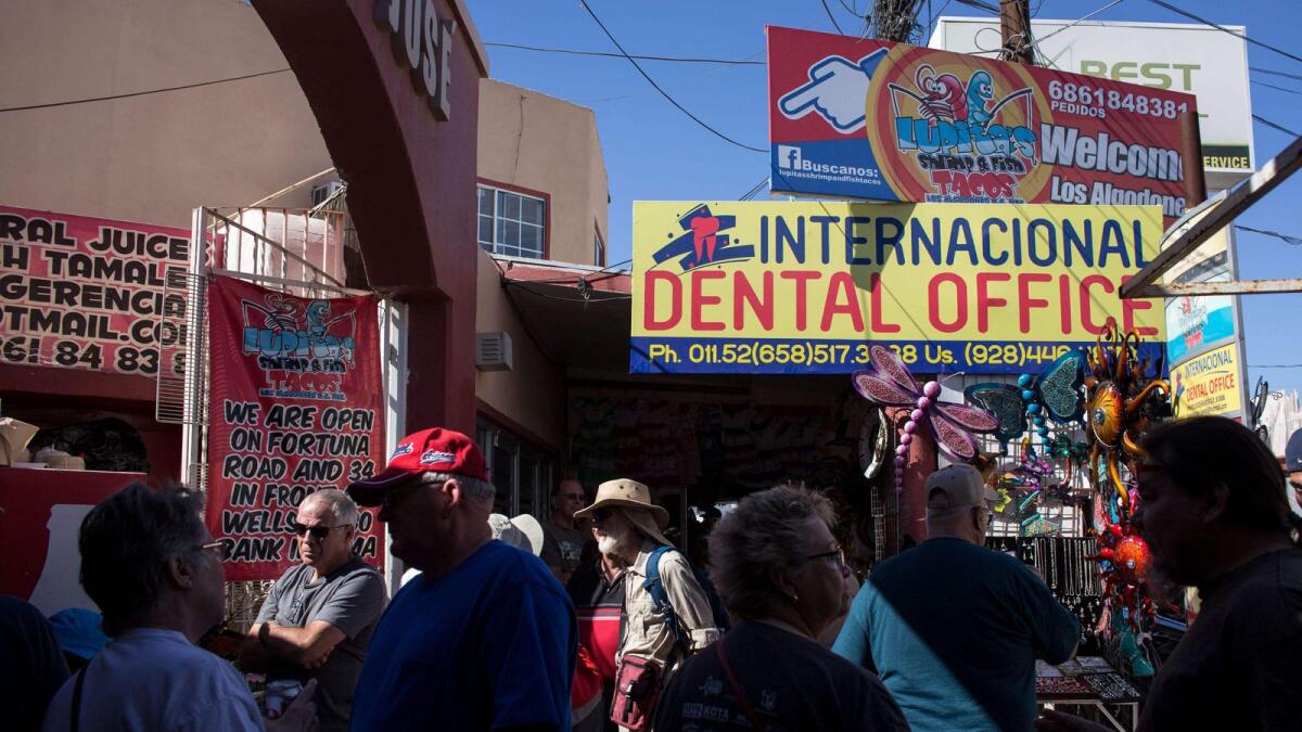 Visitors from the United States walk past a dental office in downtown Los Algodones, in Mexico on February 15, 2017.