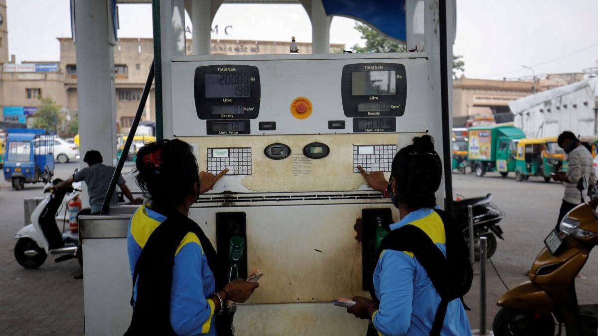 Workers enter the amount into a fuel pump machine before filling up the vehicles at a petrol station in Ahmedabad. — Reuters file
