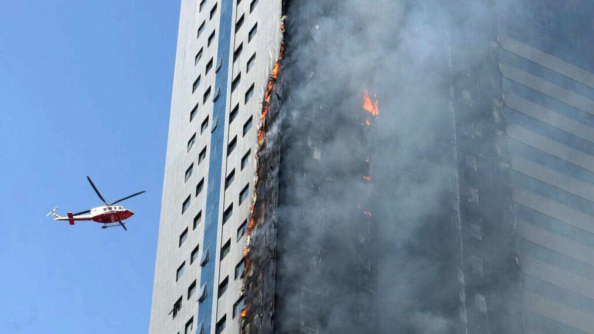 A helicopter hovers over a skyscraper which caught fire in Sharjah.