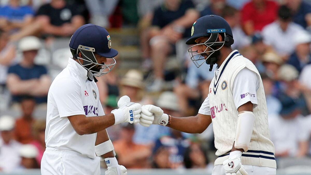 India's Ajinkya Rahane (left) and India's Cheteshwar Pujara tap gloves on the fourth day of the second cricket Test match. — AFP