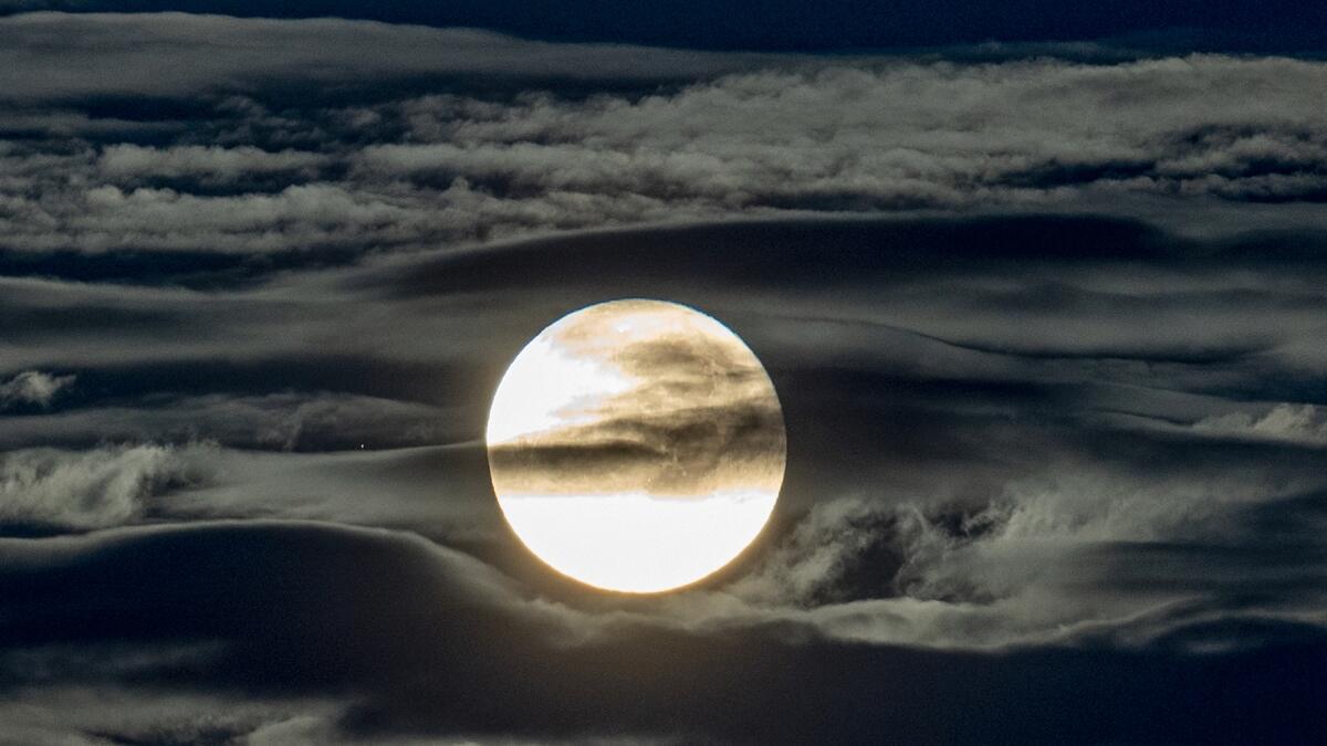 The full moon shines surrounded by clouds in the outskirts of Frankfurt, Germany. Photo: AP