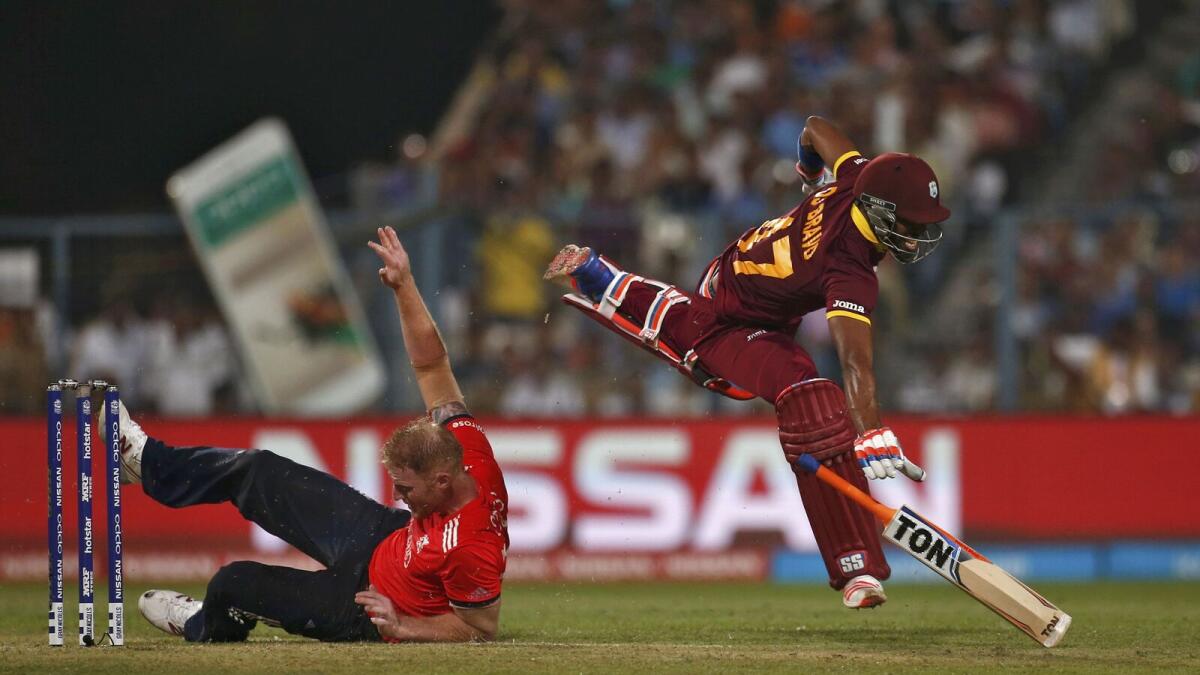 England's Ben Stokes falls over after colliding with West Indies Dwayne Bravo.