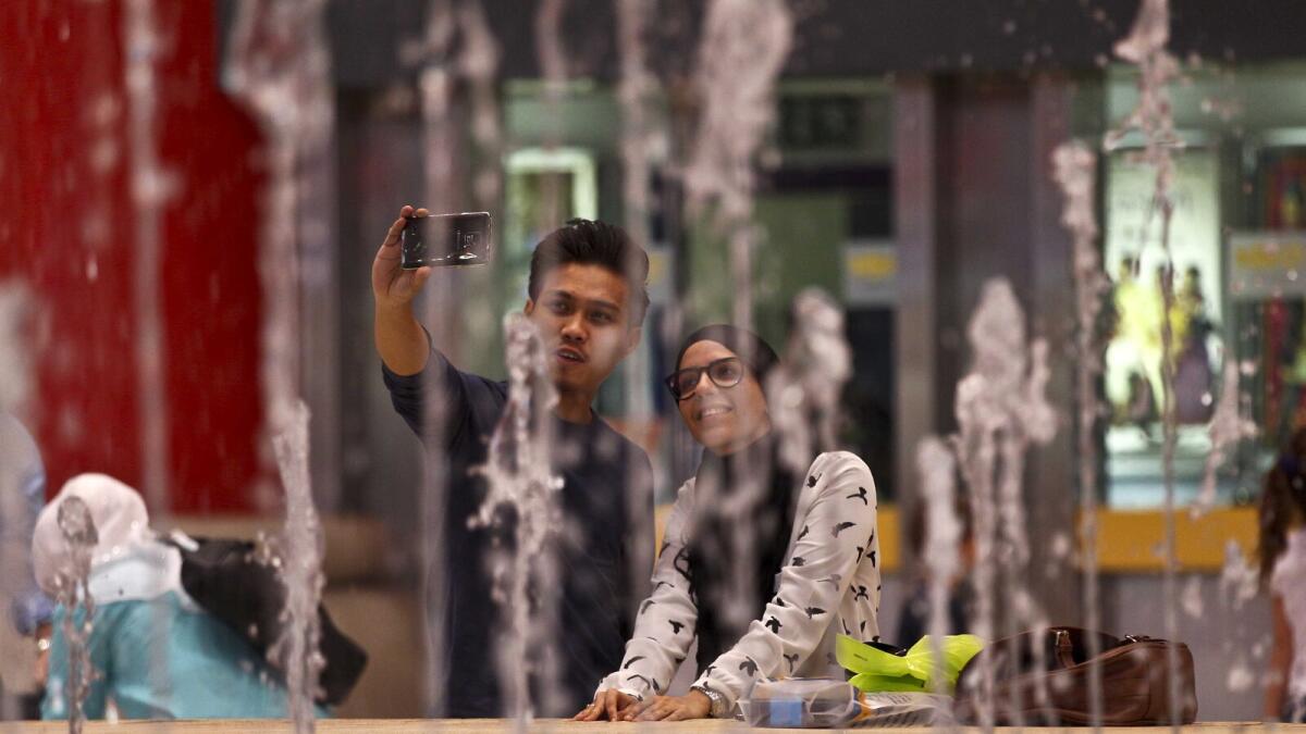 A couple clicking a selfie behind the water fountain at the Ibn Battuta Mall in Dubai. 