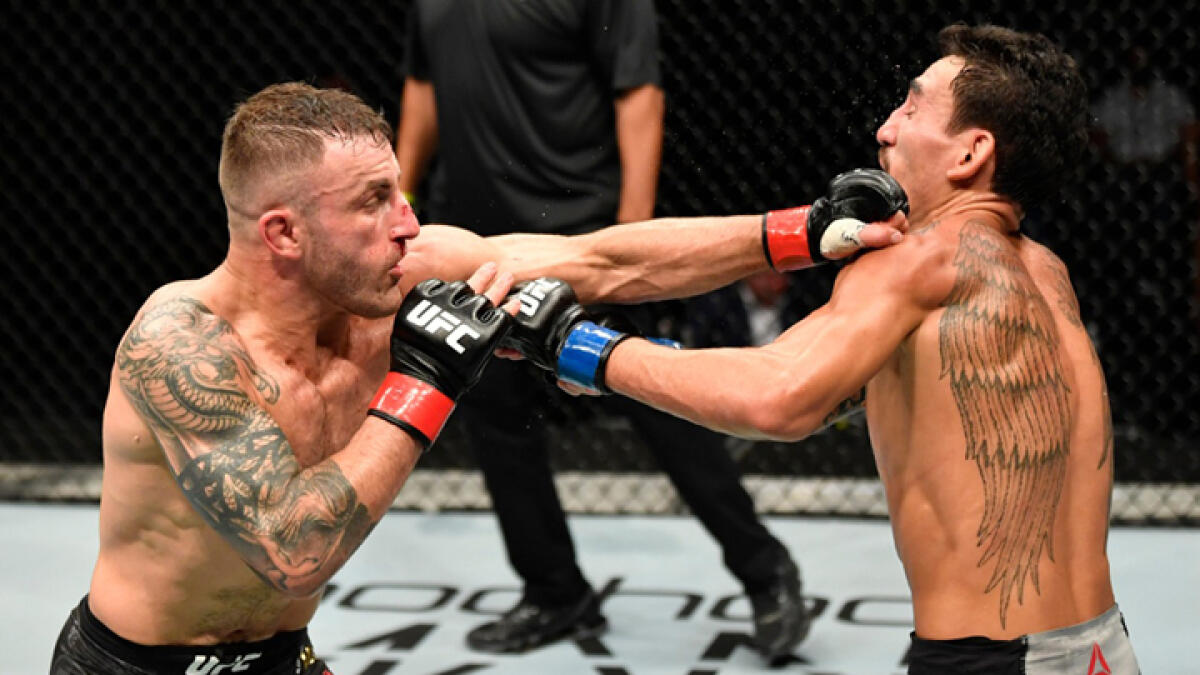 Alexander Volkanovski of Australia punches Max Holloway in their UFC featherweight championship fight during the UFC 251 event in Abu Dhabi. - Reuters