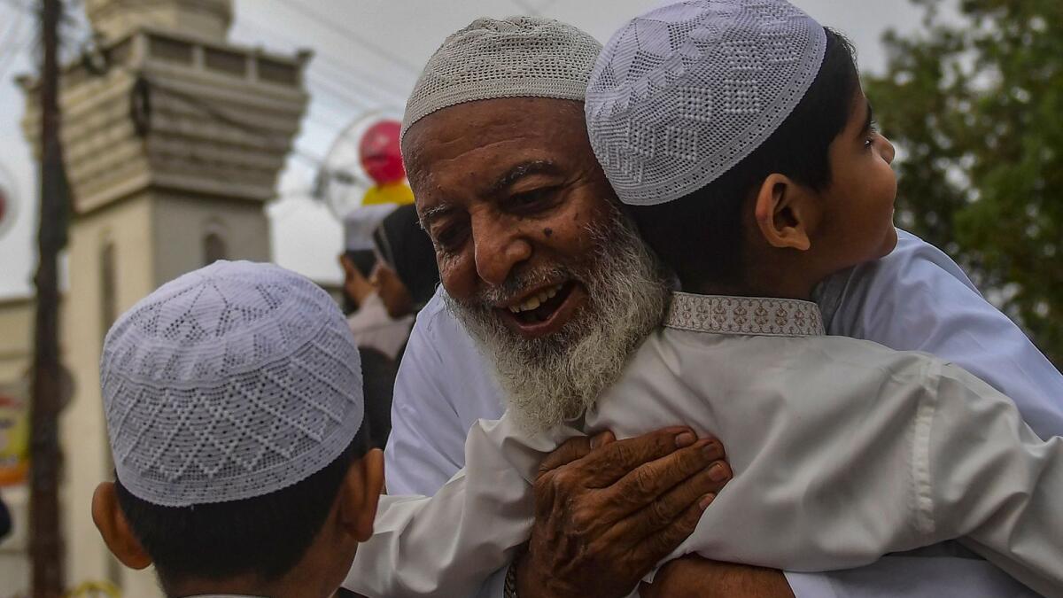 An elderly Muslim man exchanges greetings with children after offering special Eid prayers in Karachi. Photo: AFP