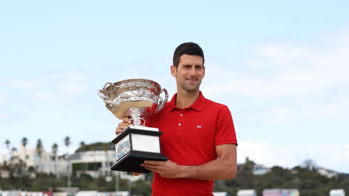 Australian Open champion Serbia's Novak Djokovic poses with the trophy during a photo shoot at Brighton Beach. — Reuters