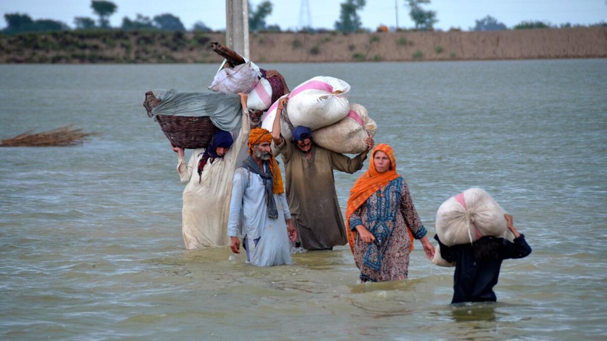A displaced family wades through a flooded area after heavy rainfall in a district of Pakistan's southwestern province. –AP