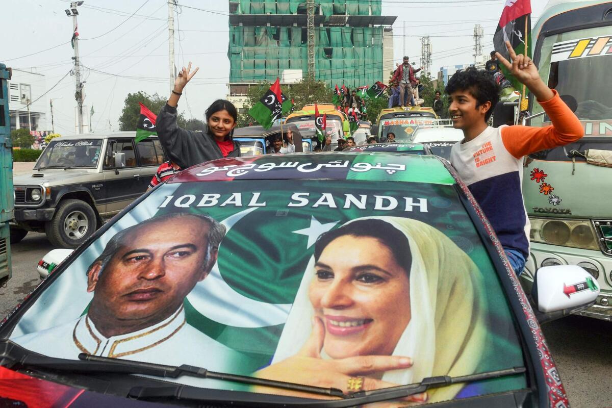 Supporters of Pakistan Peoples Party ride a car with a poster of the country’s former premiers Zulfikar Ali Bhutto (L) and Benazir Bhutto during an election campaign rally in Karachi. — AFP file