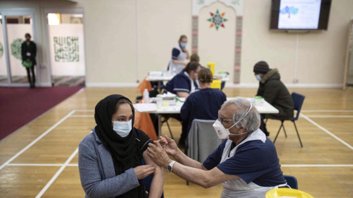 A health worker administers a dose of Covid-19 vaccine to a patient at a vaccination centre set up at the Karimia Institute Islamic centre and Mosque in Nottingham. — AFP