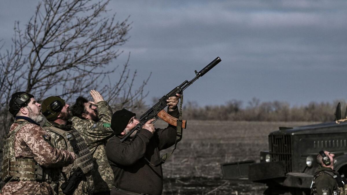 A Ukrainian serviceman fires with his rifle at a drone flying above their position near Bakhmut. — AFP file