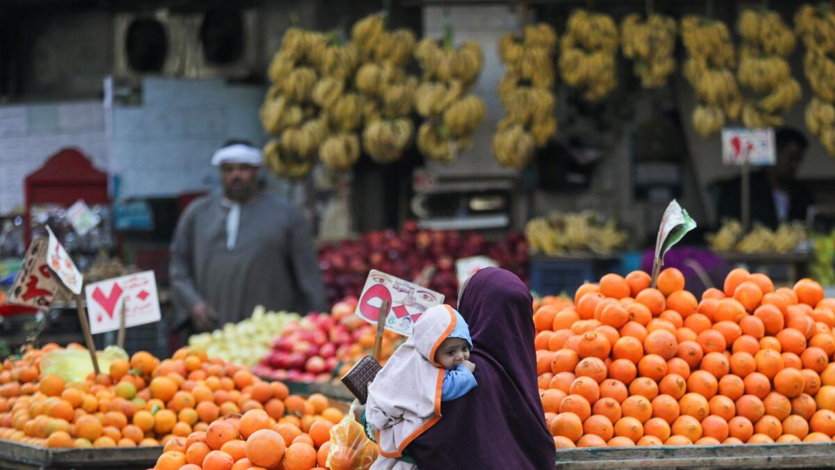 A woman holding her baby shops at a vegetable market in Cairo. The median forecast in a Reuters poll of 15 economists had projected inflation of 20.50 per cent. — Reuters
