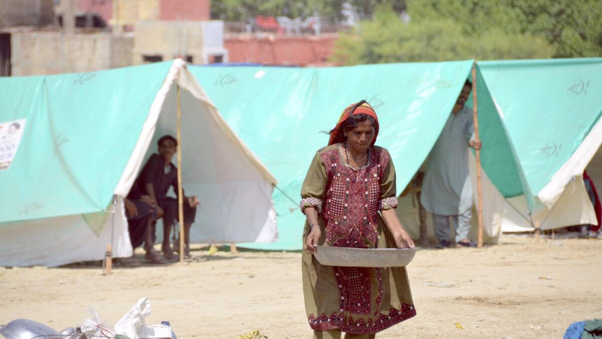 A pregnant woman carries water as she take a refuge at a camp after leaving her flood-hit homes in Jaffarabad, a district of Balochistan province. — AP