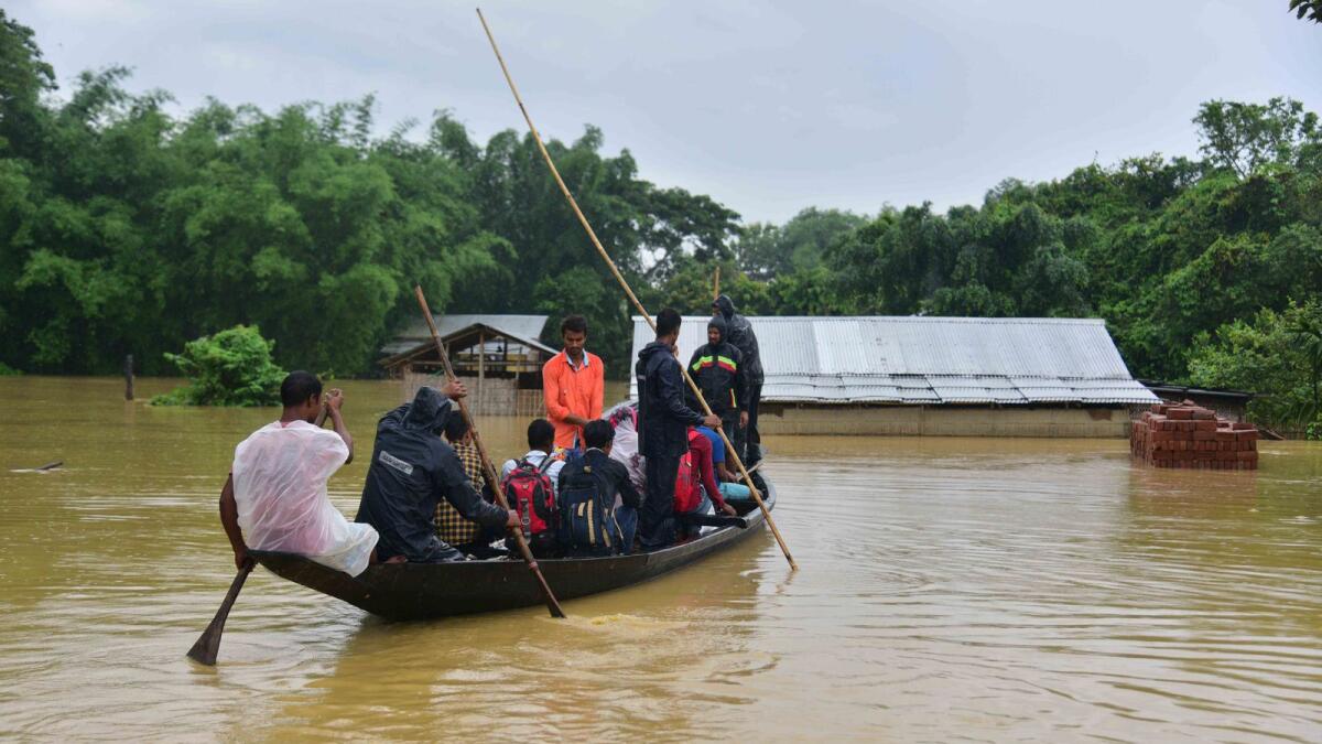 People travel on a boat through flood waters following heavy monsoon rainfalls in Nagaon district in India's Assam state. Photo: AFP