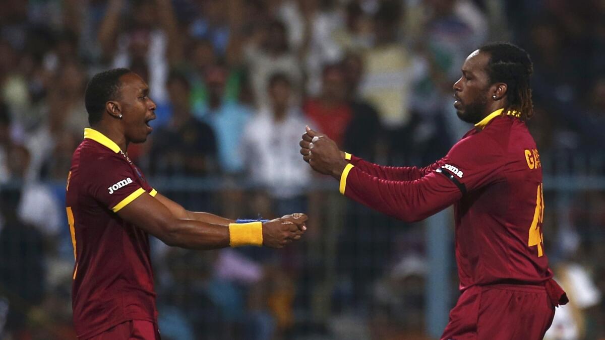 est Indies Dwayne Bravo (L) celebrates with his teammate Chris Gayle after taking the wicket of England's Ben Stokes.