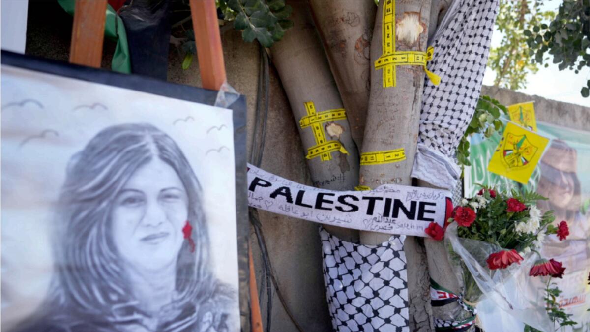 Yellow tape marks bullet holes on a tree and a portrait and flowers create a makeshift memorial, at the site where Shireen Abu Akleh was shot and killed in the West Bank city of Jenin. — AP file