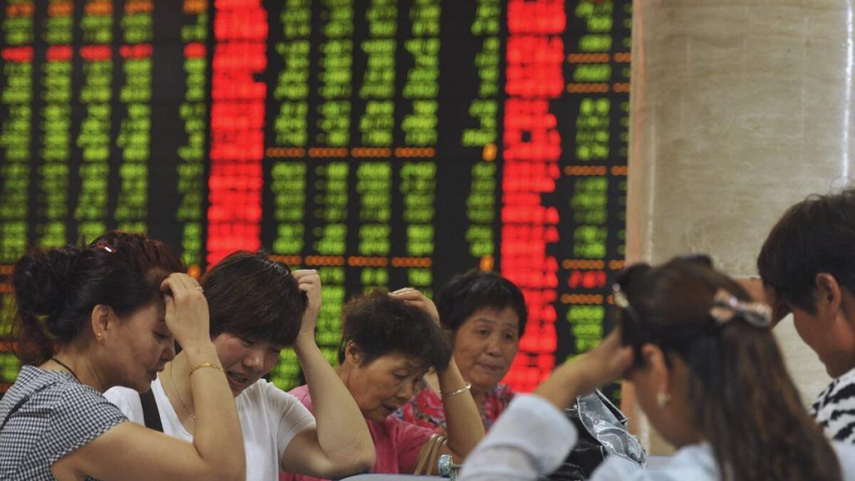 Investors react as they look at computer screens showing stock information at a brokerage house in Fuyang.