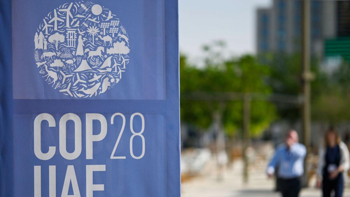 People walk past a COP28 logo ahead of the United Nations climate summit in Dubai on November 28, 2023. The UN chief urged world leaders to take decisive action to tackle ever-worsening climate change when they gather at the COP28 summit in Dubai. — AFP 