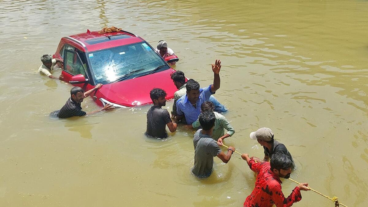 People pull a car through a water-logged road. Photo: Reuters