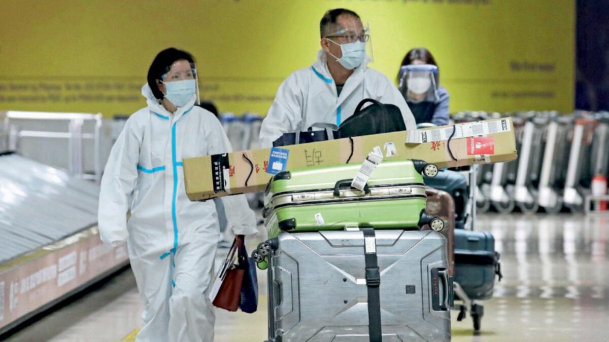 Passengers wearing protective suits walk at the arrival area of Manila's International Airport. — AP file