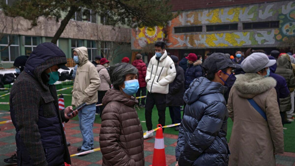 Residents wearing face masks to protect from the coronavirus line up for the coronavirus testing at a school in Fengtai District in Beijing. — AP