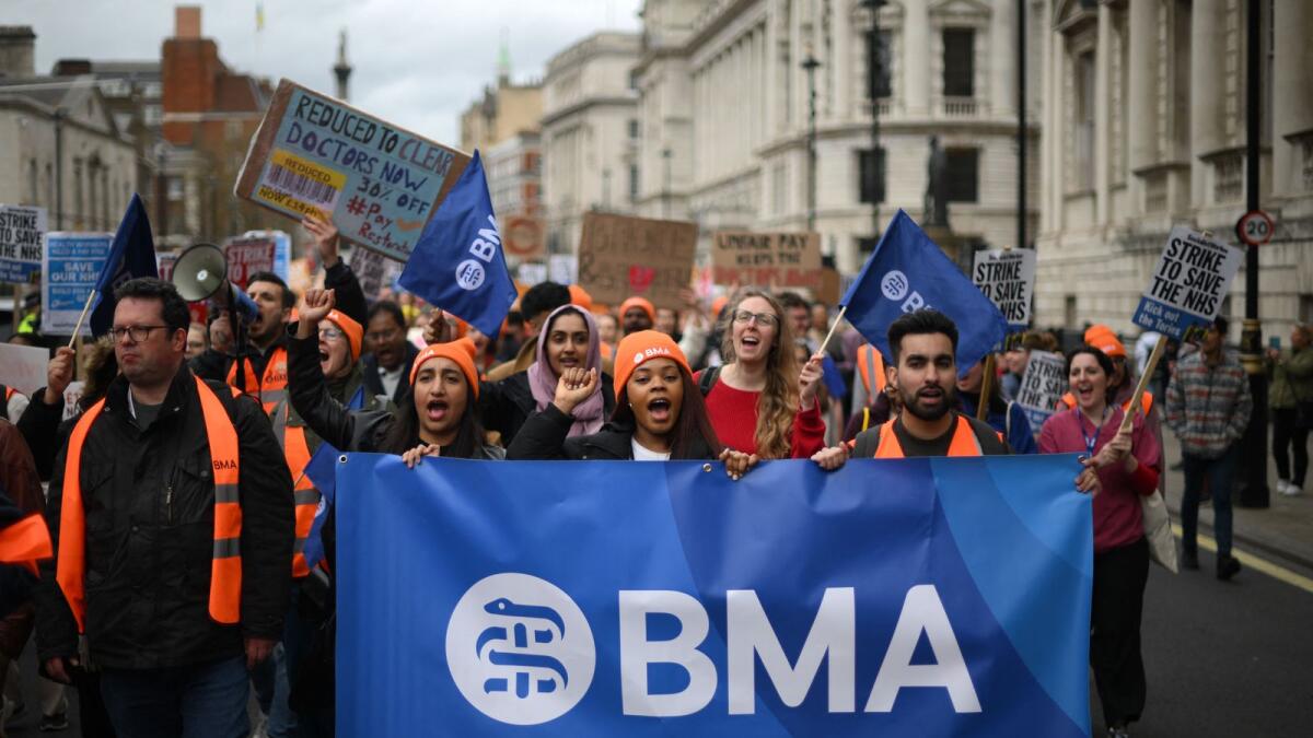 Demonstrators hold placards during a march by 'junior doctors', physicians who are not senior specialists but who may have years of experience, through central London. -  AFP