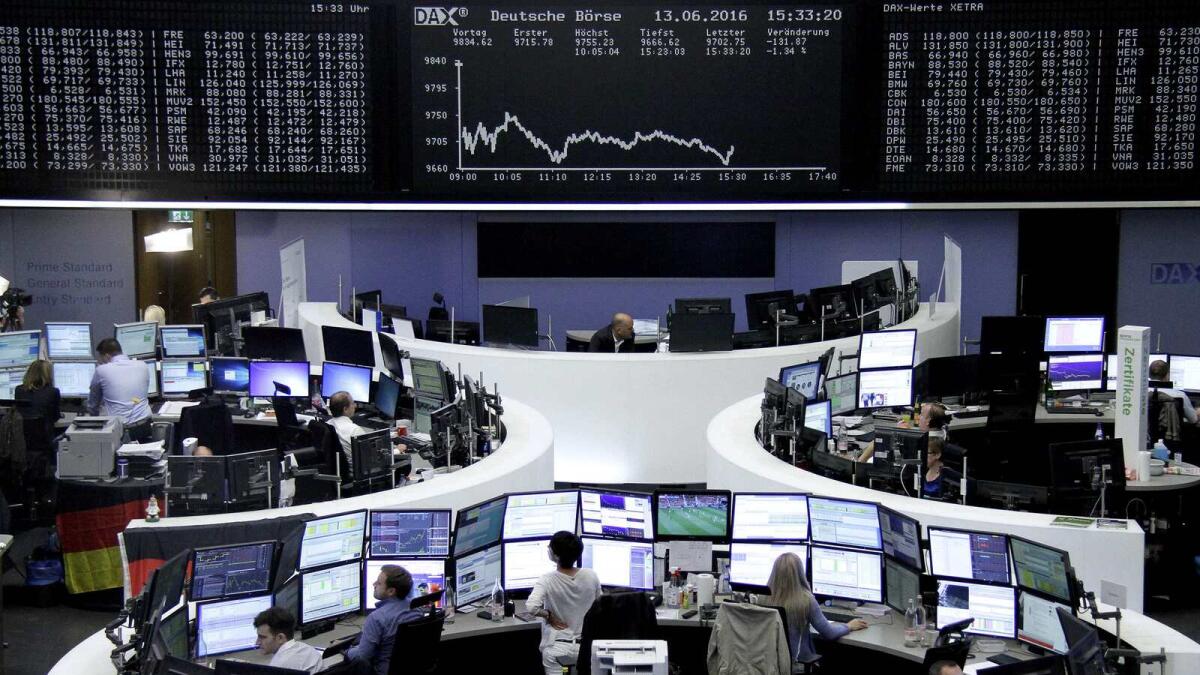 Traders work at their desks in front of the DAX board at the Frankfurt stock exchange. In Europe, Frankfurt suffered losses of more than three per cent. — Reuters
