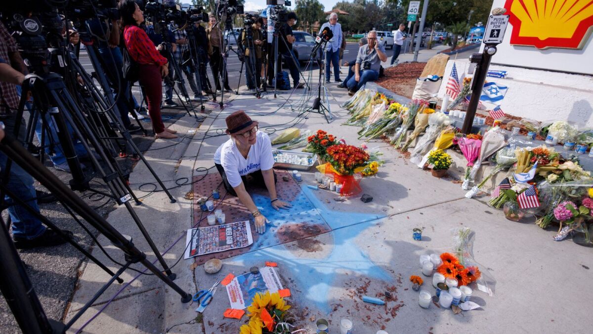 Chalk drawer Elena Colombo of the Hamakom Synagogue draws a blue star around blood at the exact location on the sidewalk of the alleged assault on Paul Kessler on Sunday in Thousand Oaks, California, U.S., November 7, 2023. Reuters