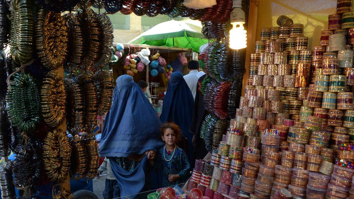 Afghan woman and child walk through a market ahead of Eid Al Fitr festivities at a local market in Jalalabad on June 22, 2017.