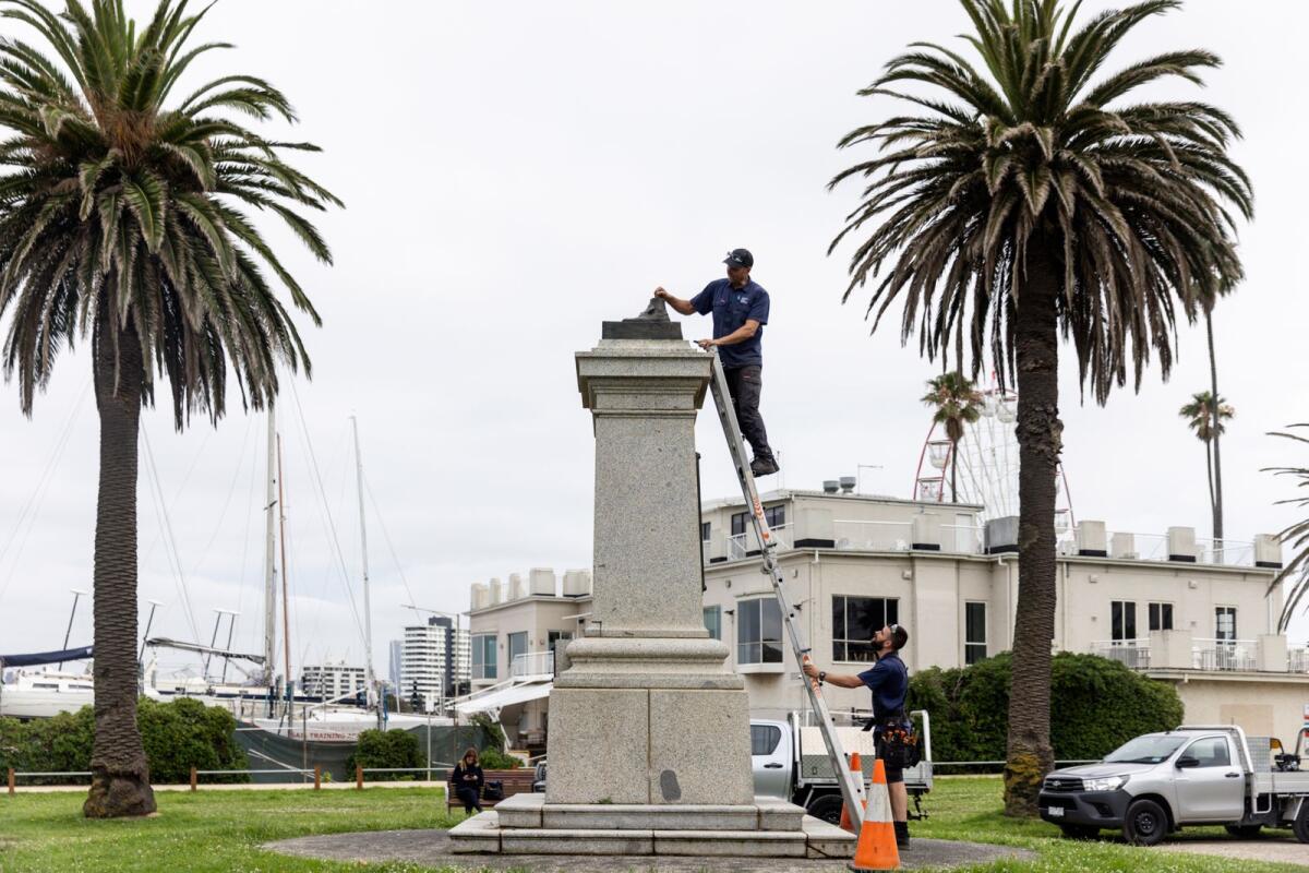Workers remove the remnants of a Captain Cook statue in Melbourne, Australia,  on Thursday after vandals cut the statue off at the ankles. — AP