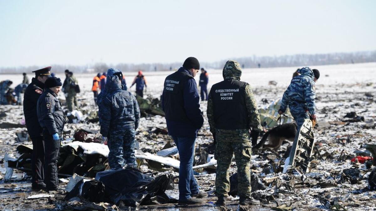 Russian Investigative Committee employees, center, and police officers investigate the wreckage of a crashed plane at the Rostov-on-Don airport, about 950 kilometers (600 miles) south of Moscow, Russia.